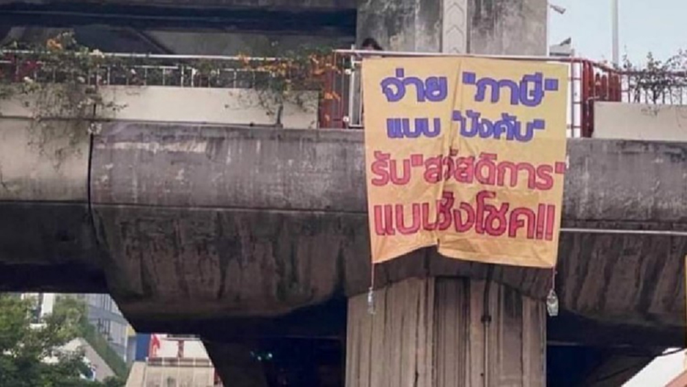 ขึงป้าย'อนุสาวรีย์ชัยฯ' จวกรัฐ “จ่ายภาษีแบบบังคับ รับสวัสดิการแบบชิงโชค”